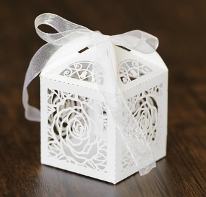 Close-up of white laser-cut hollow rose candy box with an elegant sheer ribbon tie