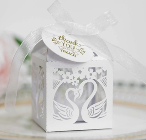 Detail of white laser-cut swan heart candy box with thank you tag and satin ribbon