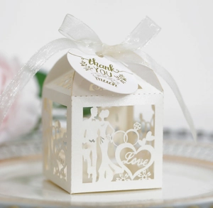 Detail view of laser-cut white wedding favor box with Thank You tag and white ribbon