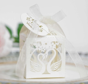Macro shot of laser-cut swan heart candy box with white organza ribbon and thank you tag