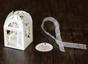 Detail of white laser-cut wedding candy box with bride groom silhouette and silver ribbon