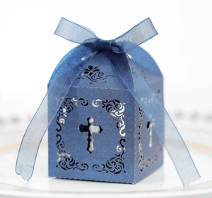 Détail boîte cadeau bleu marine découpée au laser avec motif croix et ruban élégant