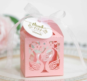 Close-up of pink hollow swan candy box with white ribbon and a gold thank you tag