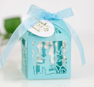 Macro detail of laser-cut light blue wedding favors box with golden thank you tag
