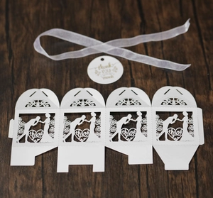 Detail of white laser-cut wedding favor box with romantic silhouette and thank you tag