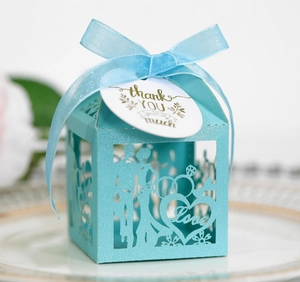 Detail of light blue laser-cut wedding favor box with ribbon and thank you tag
