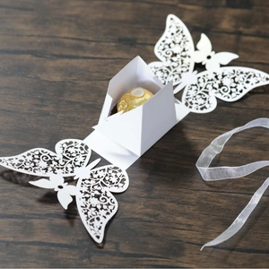 White laser-cut butterfly wedding favor box with delicate hollow design on wood background