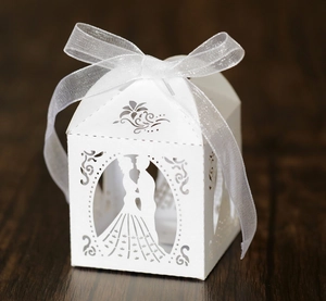 Macro view of white laser-cut wedding favor box with bride and groom silhouette detail