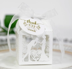 Close-up of laser cut wedding favor box with white ribbon and thank you tag