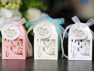 Detail of laser cut wedding favors with Mr & Mrs silhouette and ivory organza ribbons