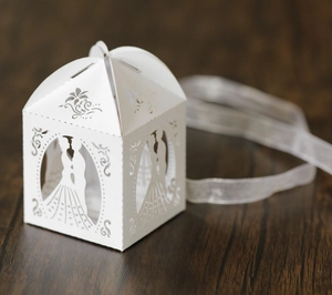 Detail of white laser-cut wedding candy box with bride and groom silhouette and ribbon