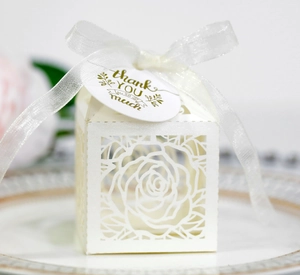 Detail of white laser-cut rose hollow candy box with ribbon and gold thank you tag