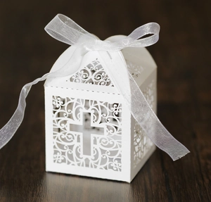Detailed laser-cut white wedding favor box with hollow cross and elegant organza ribbon