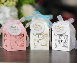 Detailed laser-cut wedding favor boxes in pink and white with Mr & Mrs ribbon bow and tag