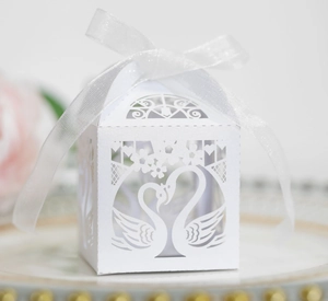 Close-up of laser-cut white swan candy box with elegant ribbon for wedding favors