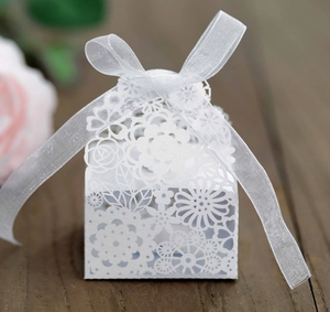 Détail macro du motif floral découpé au laser sur boîte de mariage blanche avec ruban