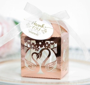 Macro view of rose gold laser-cut swan heart candy box with white silk ribbon and tag