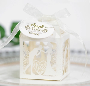 Close-up of white laser-cut wedding favor box with silhouette design and thank you tag