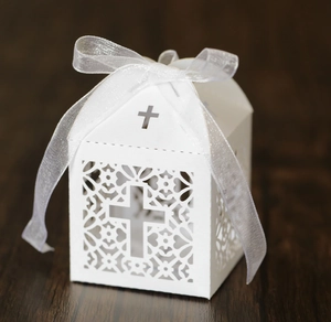 Détail de la boîte à dragées blanche découpée au laser avec croix et ruban en satin