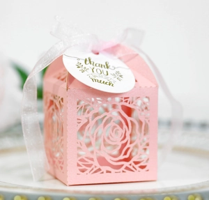 Close-up of pink laser-cut candy box with rose pattern, organza ribbon, and thank you tag