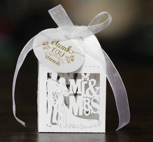 Macro detail of white laser-cut Mr & Mrs wedding favor box with thank you tag and ribbon