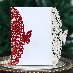 Detailed laser-cut wedding invitation featuring butterfly floral patterns and red glitter