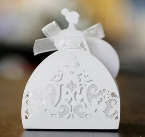 Macro shot of white laser-cut bridal dress paper favor box with intricate lace details