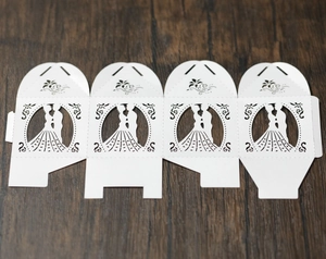 Macro detail of laser-cut white wedding favor box showing bride and groom silhouette
