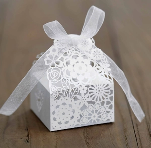 Détail de motifs floraux découpés au laser sur boîte cadeau blanche avec ruban organza
