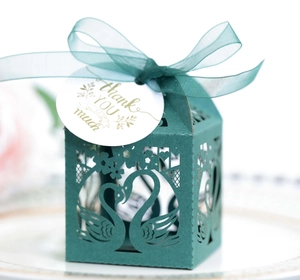 Detail of laser-cut swan design on dark green favor box with thank you tag