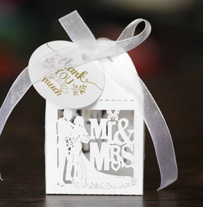 Close-up of laser-cut Mr & Mrs wedding favor box with white ribbon and thank you tag