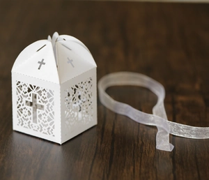 Détail de boîte cadeau ajourée au laser avec croix et ruban blanc élégant
