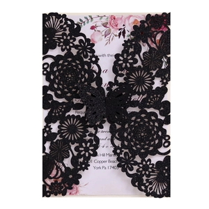 Detail of laser-cut black glitter wedding invitation with floral butterfly cutout pattern
