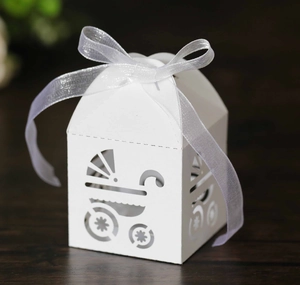 Close-up of white baby shower candy box with laser-cut stroller pattern and ribbon bow