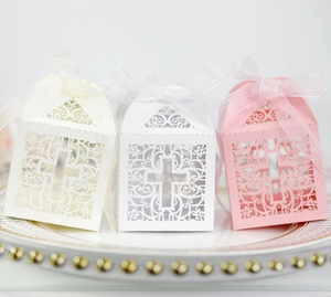 Macro view of hollow laser-cut cross candy boxes in white and pink for weddings
