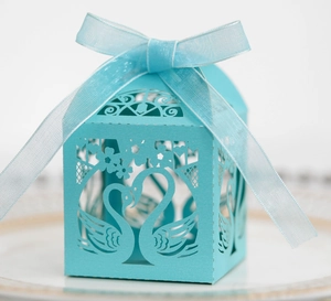 Close-up of sky blue laser-cut candy box with swan heart design and organza ribbon