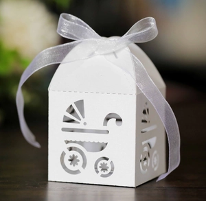 Detail of white laser-cut baby carriage candy box with organza ribbon for parties