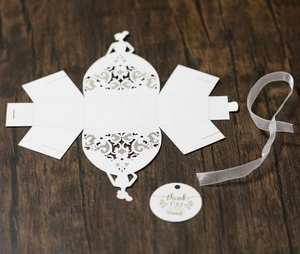Laser-cut white wedding favor box with lace details, ribbon, and thank you tag