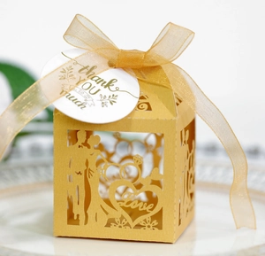 Detail of laser-cut gold wedding favor box with bride, groom, and Thank You tag
