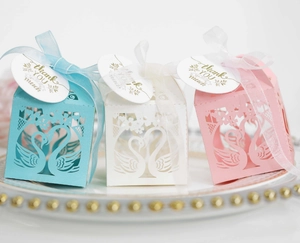 Detailed view of laser-cut swan wedding favors with elegant ribbons and thank you tags