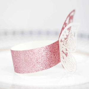 Detalle de envoltorio rosa de purpurina para cupcakes con mariposa blanca cortada a láser