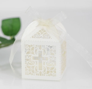 Close-up of white laser-cut hollow cross candy box with ribbon and floral patterns