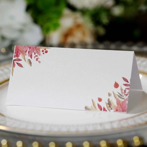 Detailed view of elegant folding place card with autumn leaf patterns on a dinner plate