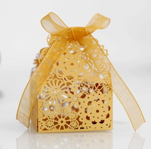 Détail macro du motif floral découpé au laser et du ruban organza sur la boîte dorée