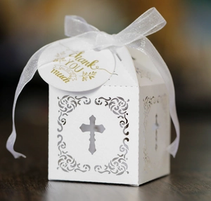Gros plan d'une boîte à bonbons découpée au laser avec croix blanche et ruban de mariage