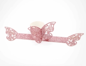 Detalle de servilletero de mariposa con purpurina rosa y diseño de papel calado