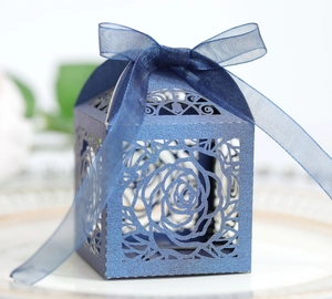 Detail of laser-cut rose hollow favor box in navy blue pearl paper with silk ribbon