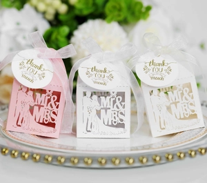 Close-up of pink and white hollow laser-cut wedding favor boxes with ribbons and tags