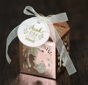 Detail of rose gold laser-cut favor box featuring a rider silhouette and white silk ribbon