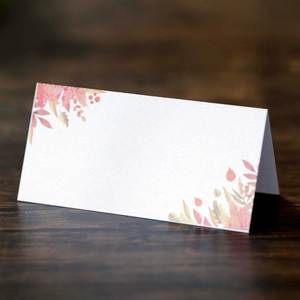 Detail of pearl white folded table card featuring autumn maple leaf and berry printing